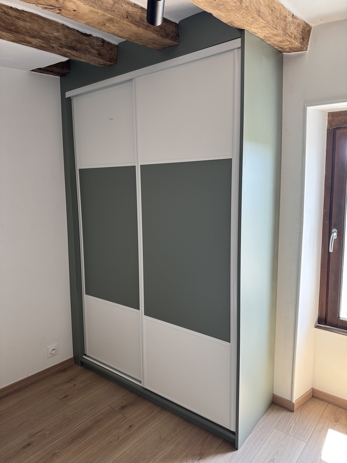 Placard sur mesure à portes coulissantes blanches et vert gris sous poutres