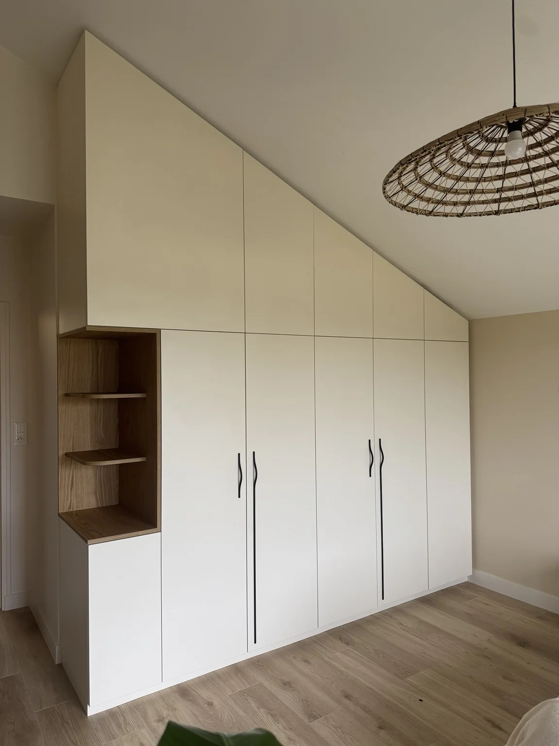 Agencement sur mesure sous pente avec placards blancs et niche en bois